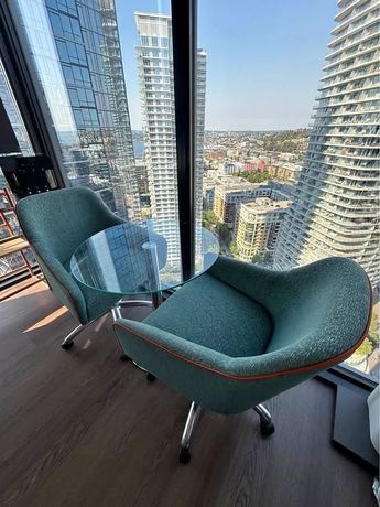Pair rolling adjustable vintage fabric arm chairs in light teal/orange cording and round glass table